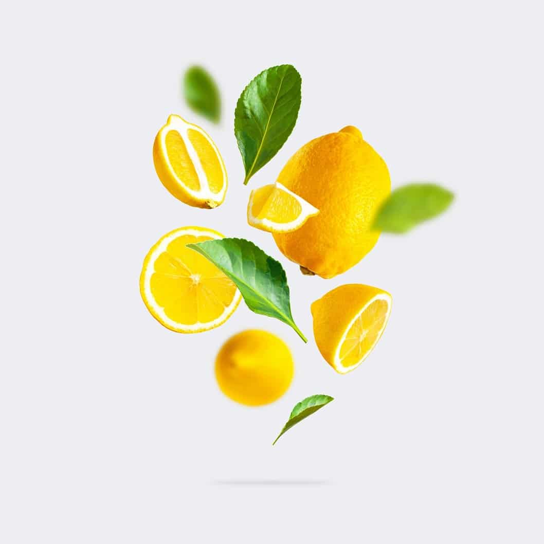 Juicy,Ripe,Flying,Yellow,Lemons,,Green,Leaves,On,Light,Gray