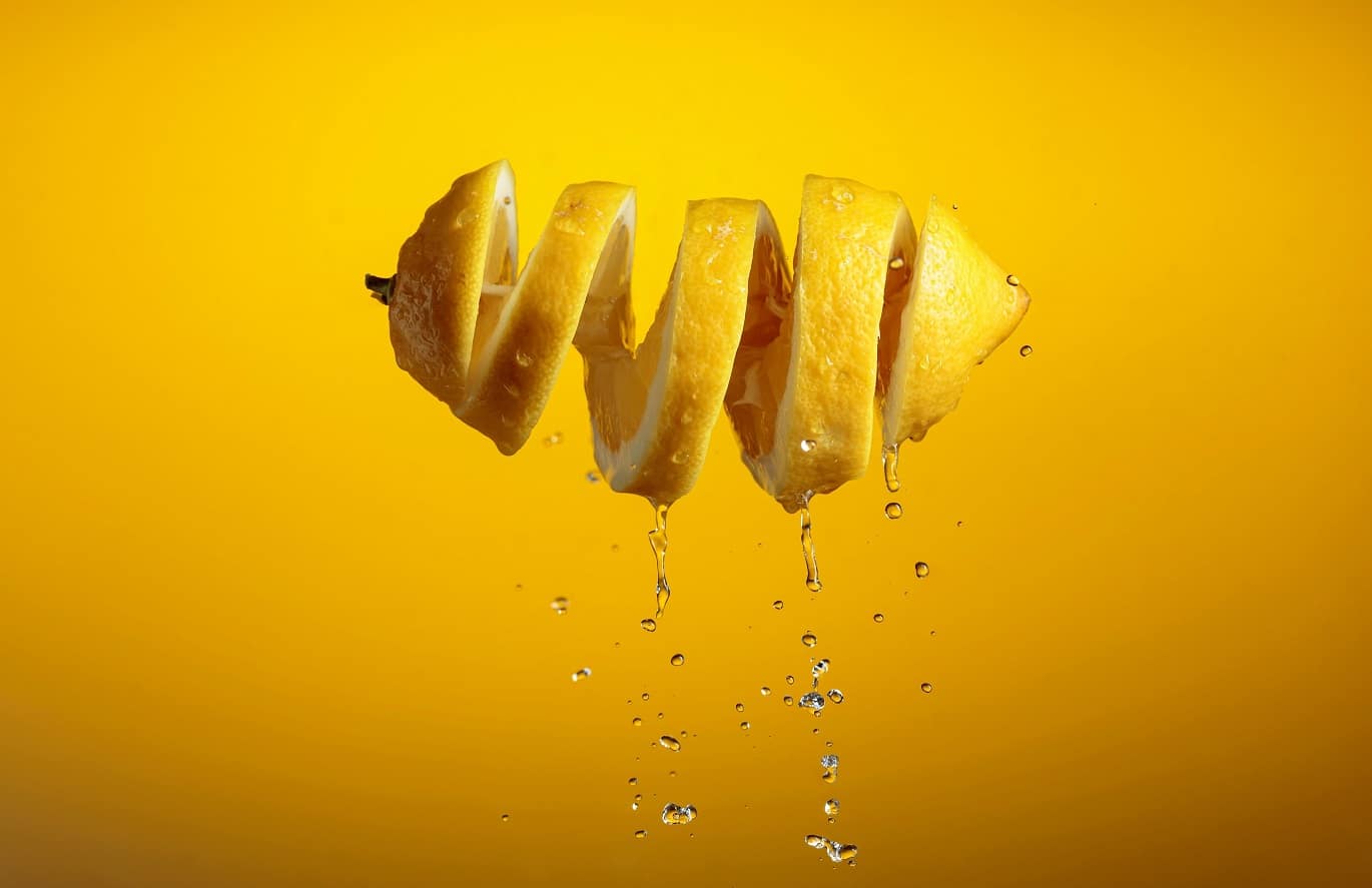 Fresh,Cut,Lemon,And,Drops,Of,Juice,On,A,Yellow